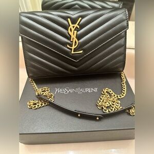 Cassandre Envelope Chain wallet in black grained leather with gold hardware.